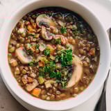 Nahaufnahme eines Linsen- und Pilz-Eintopfs, der die erdigen Pilze und zarten Linsen hervorhebt.